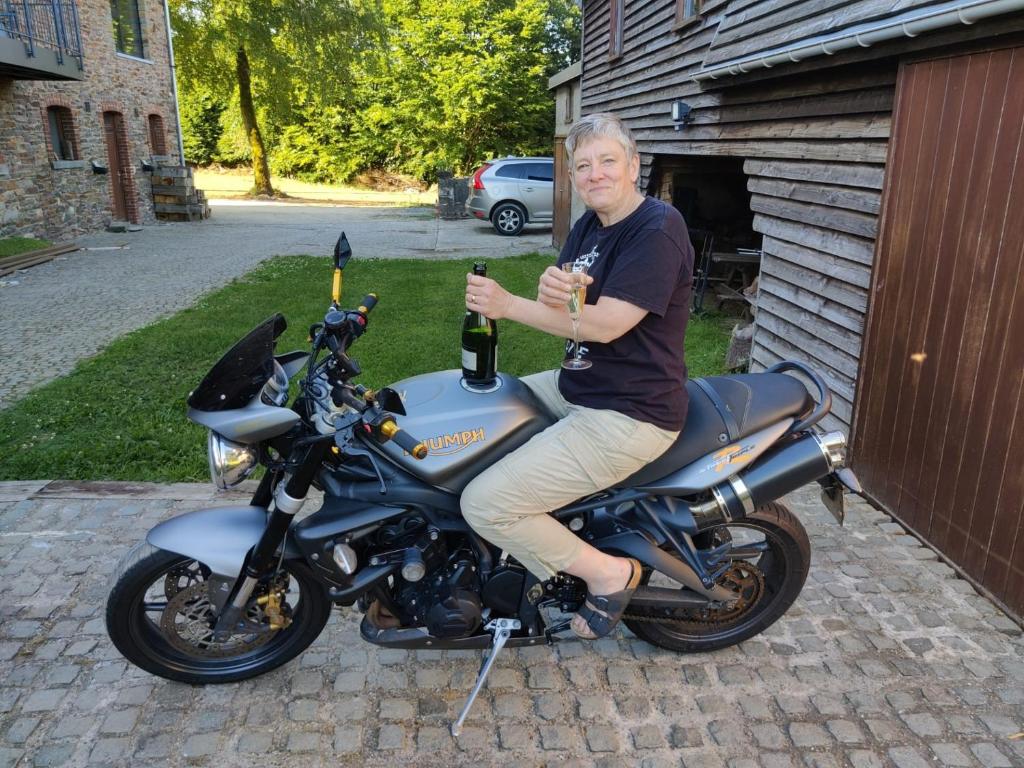 a man sitting on a motorcycle with a bottle of wine at Le Buisson B&amp;B in Gouvy