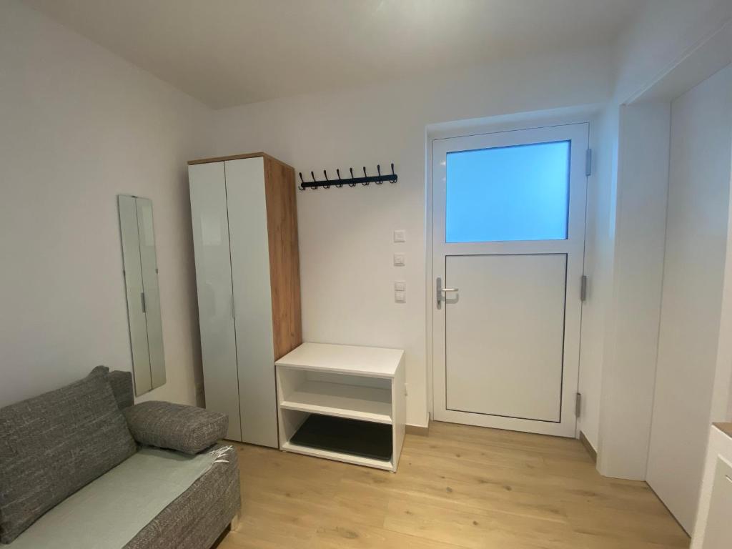 ein Wohnzimmer mit einem Sofa, einem Fenster und einer Tür in der Unterkunft Apartment S&A in Holzkirchen