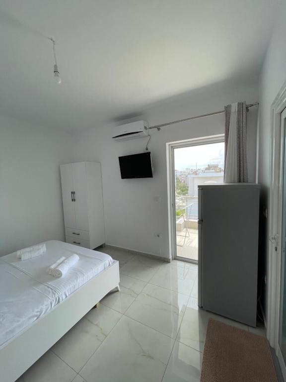 a white bedroom with a bed and a television at Villa Angelina Ksamil in Ksamil
