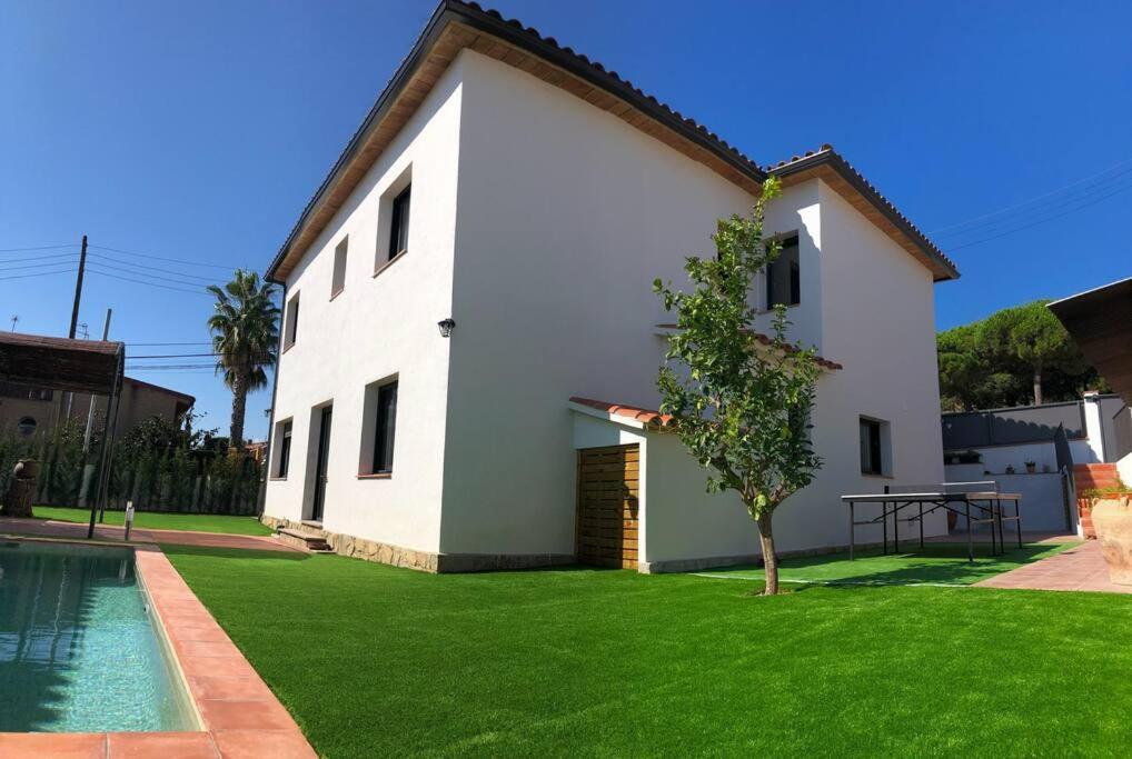 uma casa branca com um quintal e uma piscina em CASA CENTRO DEL PUEBLO CON PISCINA PRIVADA em Sant Vicenç de Montalt