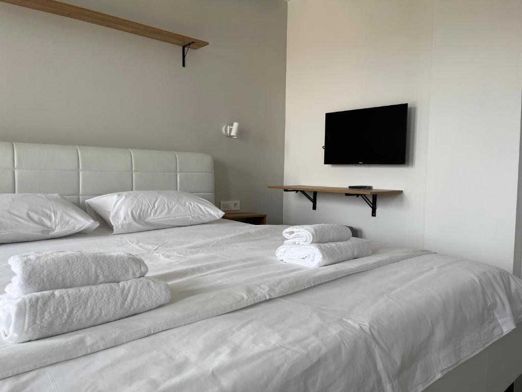 białe łóżko z 3 białymi poduszkami i telewizorem w obiekcie Apartments Joana w Ochrydzie