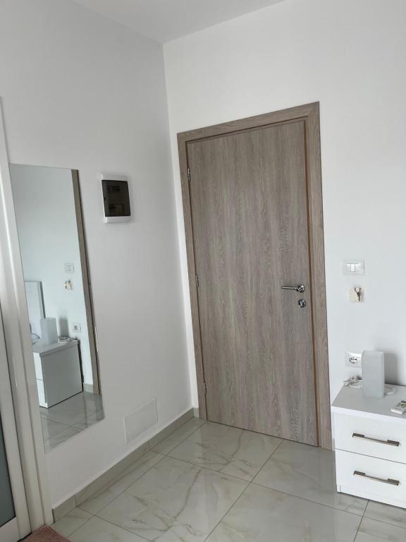 a bathroom with a wooden door and a mirror at Villa Angelina Ksamil in Ksamil