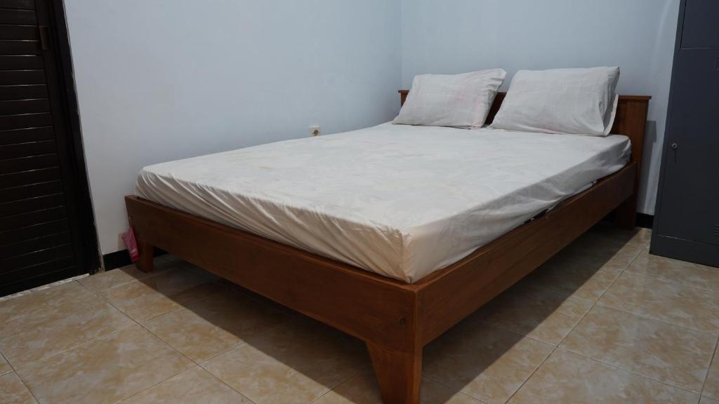 a bed with white sheets and pillows on it at OYO 92744 Coconut Island Homestay & Resort in Pasanggaran