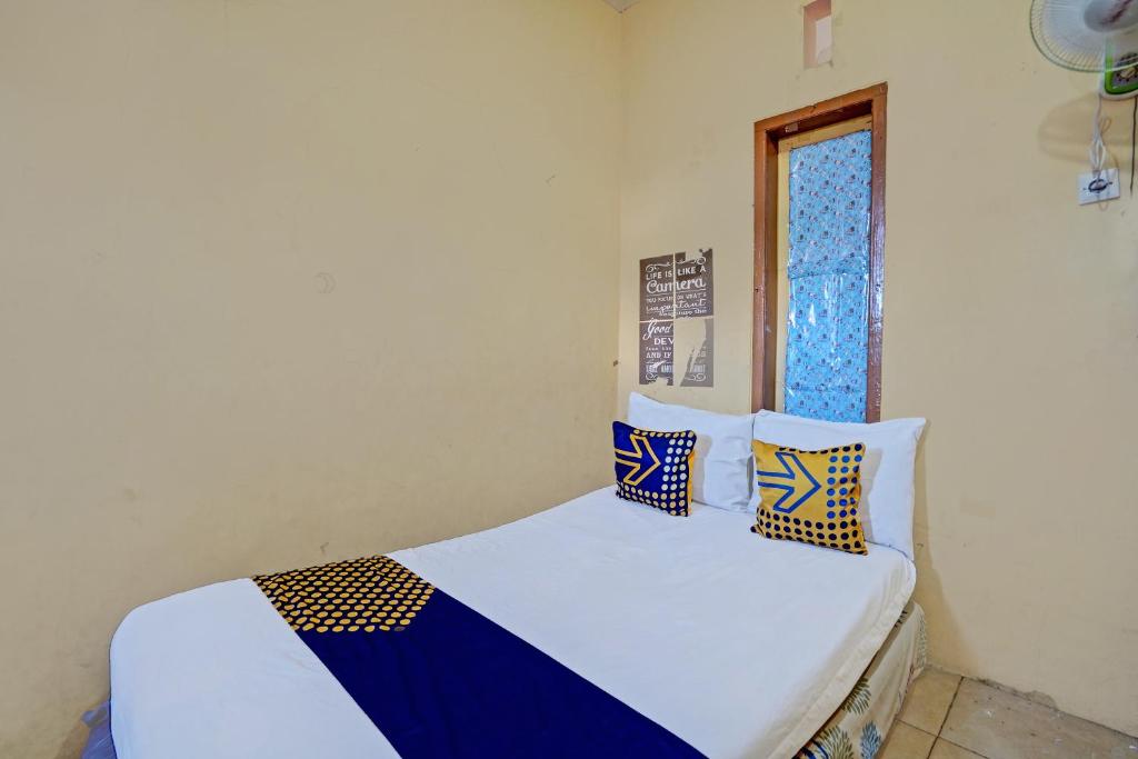 SPOT ON 92730 Lili Kost Syariah في بانيووانجى: سرير مع وسائد زرقاء وبيضاء ونوافذ