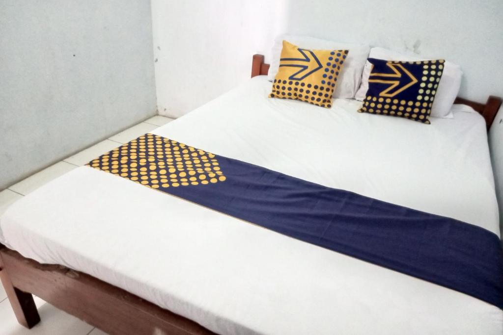 two beds in a room with blue and yellow pillows at SPOT ON 92743 Kost Elisabeth Syariah in Ngadipuro