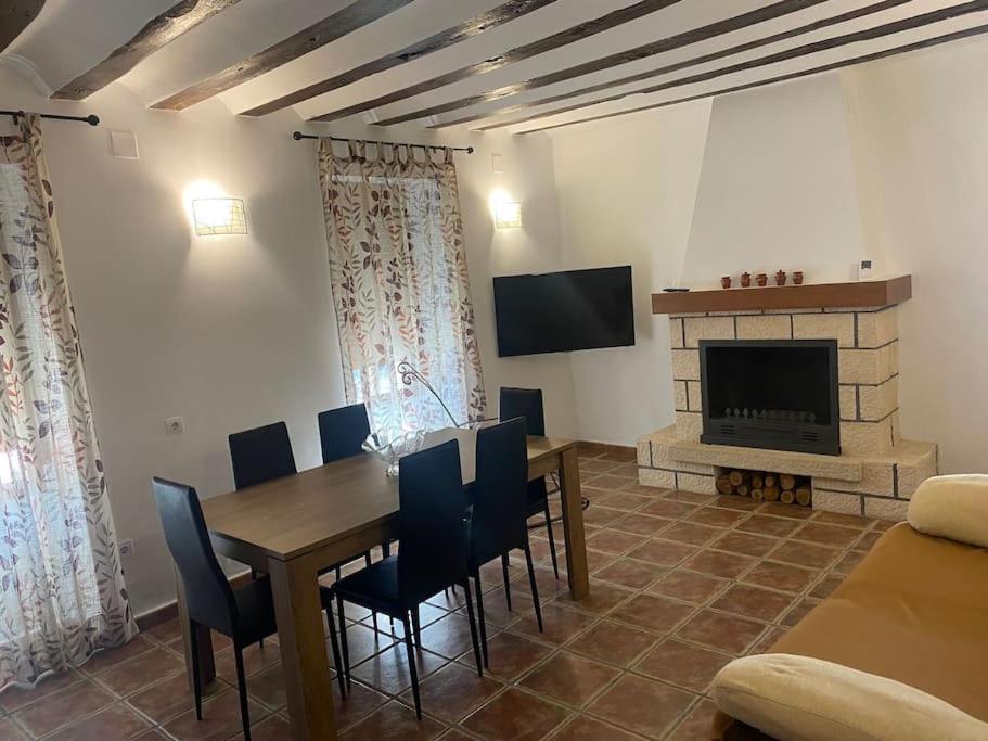 una sala da pranzo con tavolo, sedie e camino di Agradable casa con chimenea interior y barbacoa. a Graja de Iniesta