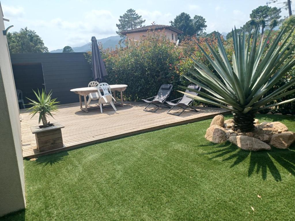 une arrière-cour avec une terrasse en bois dotée de deux chaises et d'une table dans l'établissement Mini villa a Lecci, Proche de la mer, à Lecci