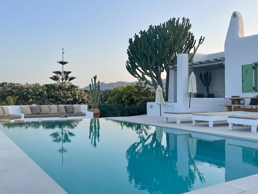 Molos ParouにあるVilla Maria Paros - A Unique & Luxurious Villa - Beach in Walking Distanceの白い家具付きのスイミングプールが備わるヴィラです。