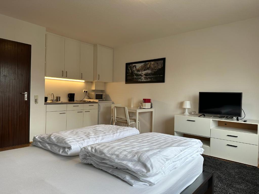 a white bedroom with a bed and a kitchen at Studio Apartment near Linz Main Train Station in Linz