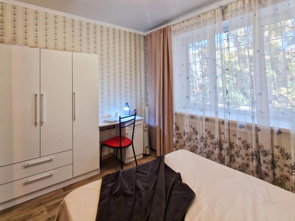 ein Schlafzimmer mit einem Schreibtisch und einem Bett und einem Fenster in der Unterkunft Золотой квадрат in Almaty