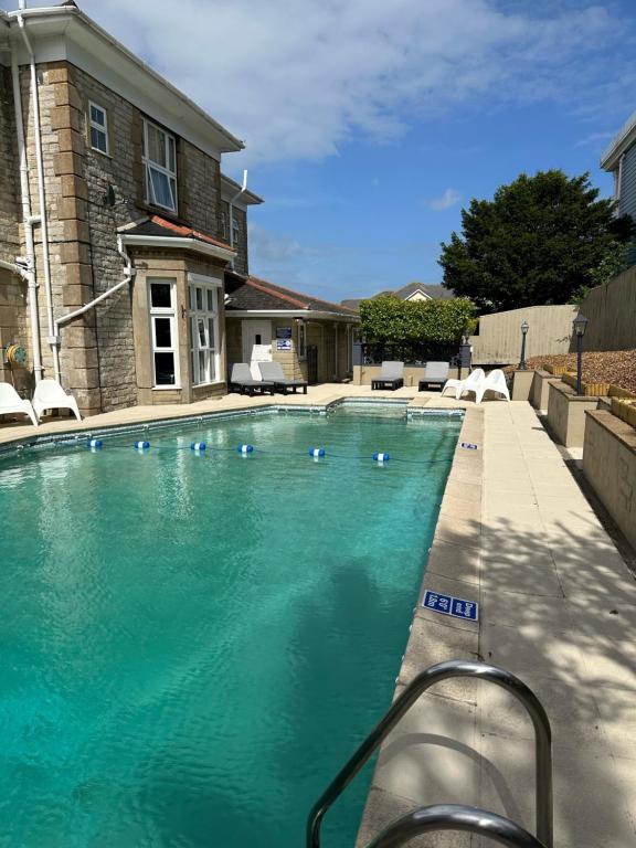 a swimming pool in front of a house at Queensmead Hotel in Shanklin