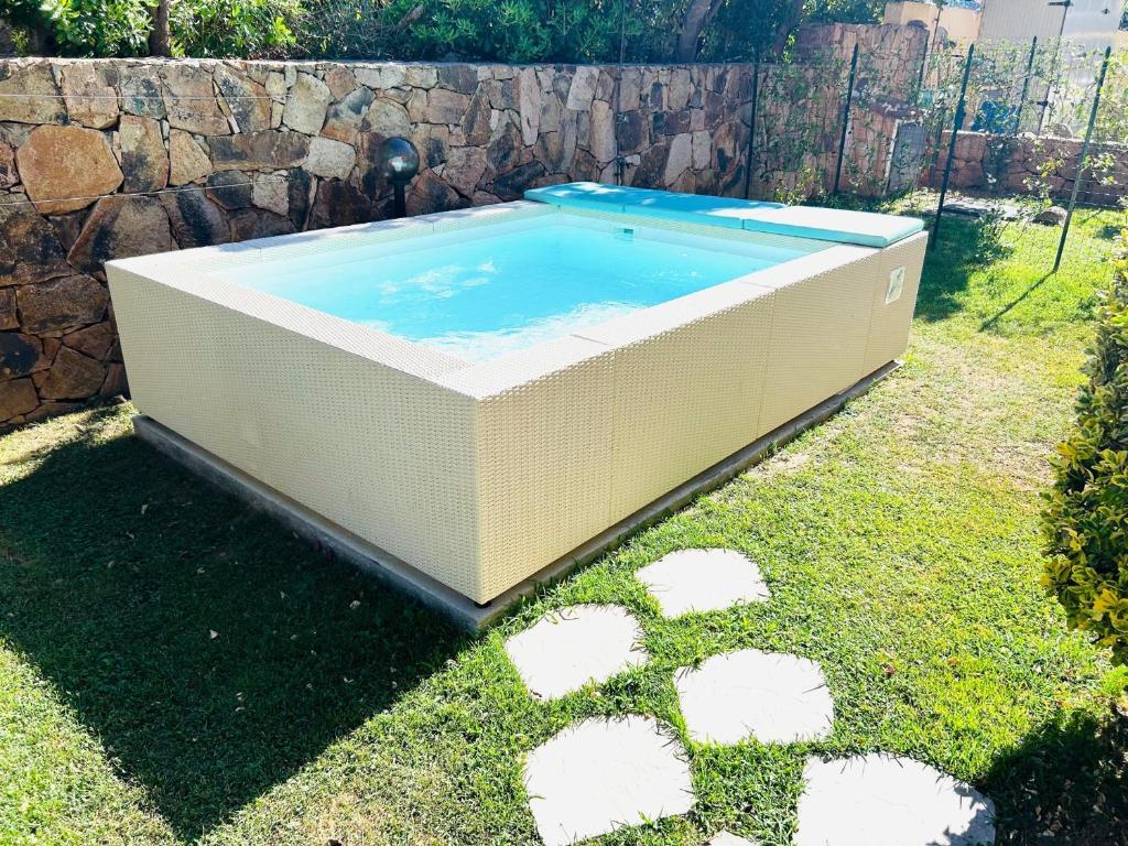 una piscina en un patio con una pared de piedra en Villetta Bouganville, en Budoni