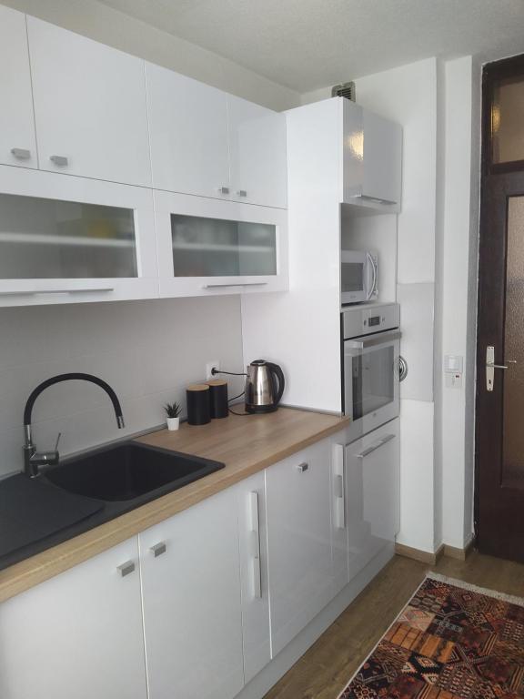 サラエボにあるUrban Nest Apartment Sarajevoの白いキャビネットとシンクのあるキッチン