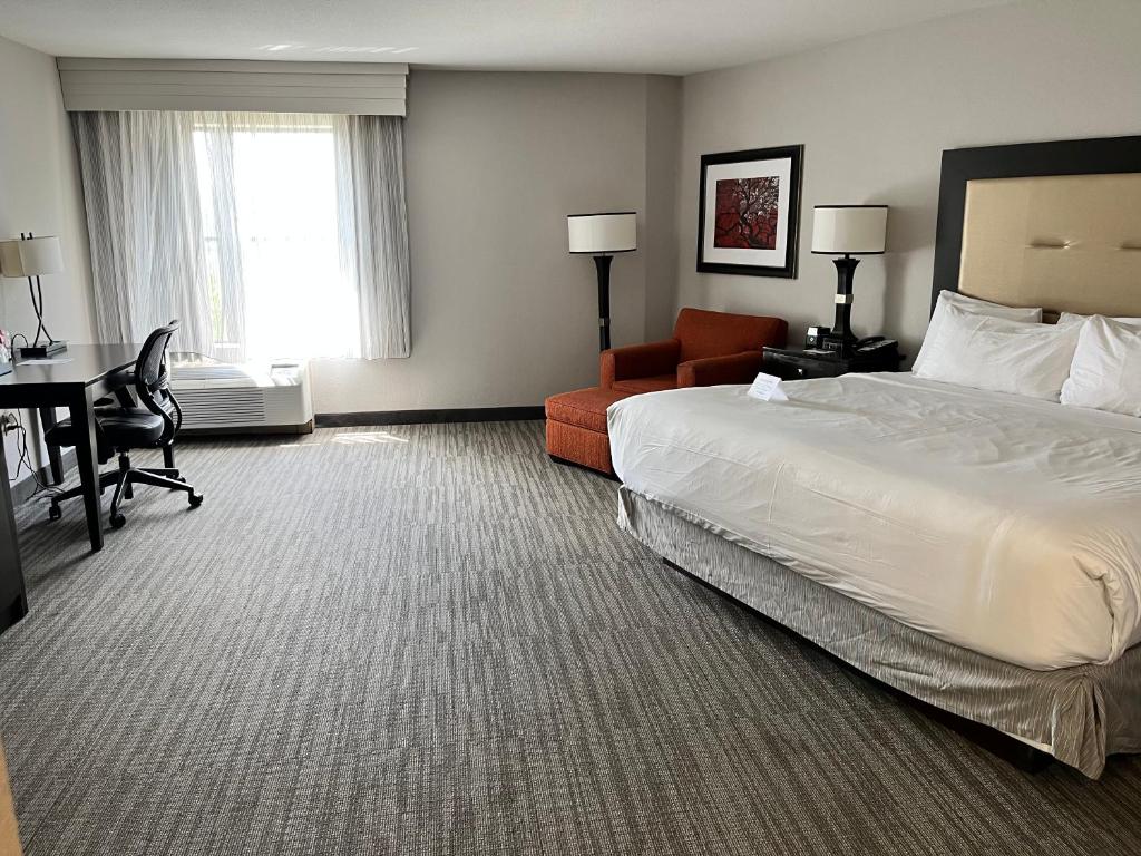 a hotel room with a bed and a chair and a desk at The Branson Hillside Hotel in Branson