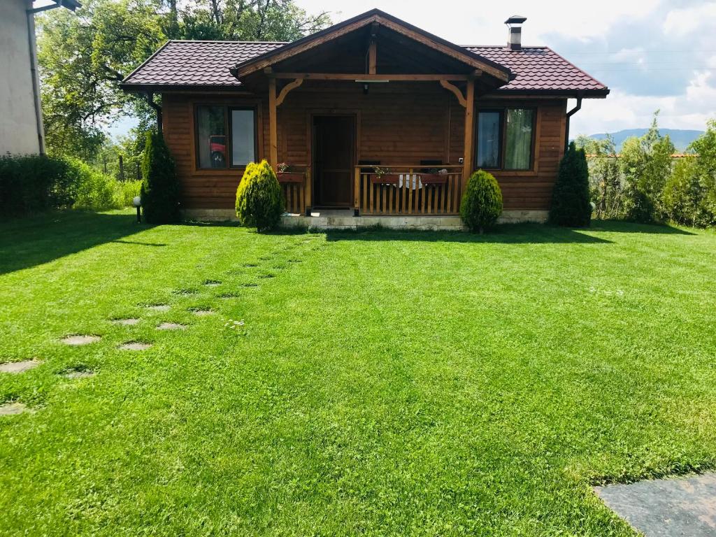 a log cabin with a lawn in front of it at Къщи за гости Михайлови in Sapareva Banya