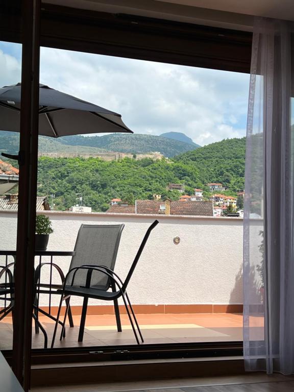 einen Balkon mit einem Stuhl und einem Sonnenschirm in der Unterkunft Zani Boutique Hotel in Prizren