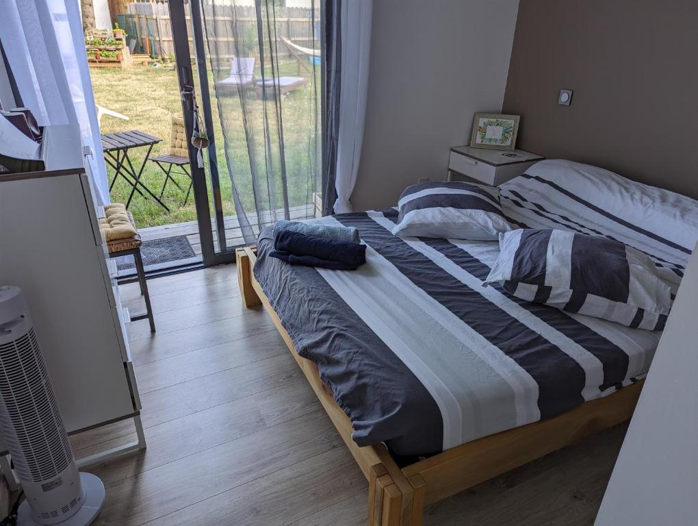 un lit dans une chambre avec une grande fenêtre dans l'établissement Chambre privée chez l'habitant, à Parentis-en-Born