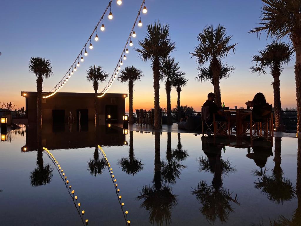 dwoje ludzi siedzących przy stole w pobliżu basenu z palmami w obiekcie 5 Stars Kamala Beach Resort D49 w mieście Kamala Beach