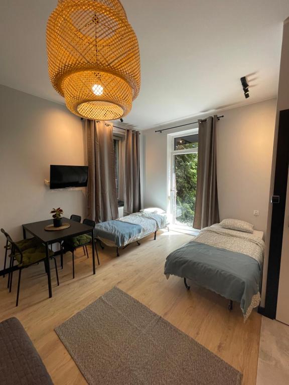 Pokój z 2 łóżkami, stołem i żyrandolem w obiekcie Vacation Apartments Sopot w mieście Sopot