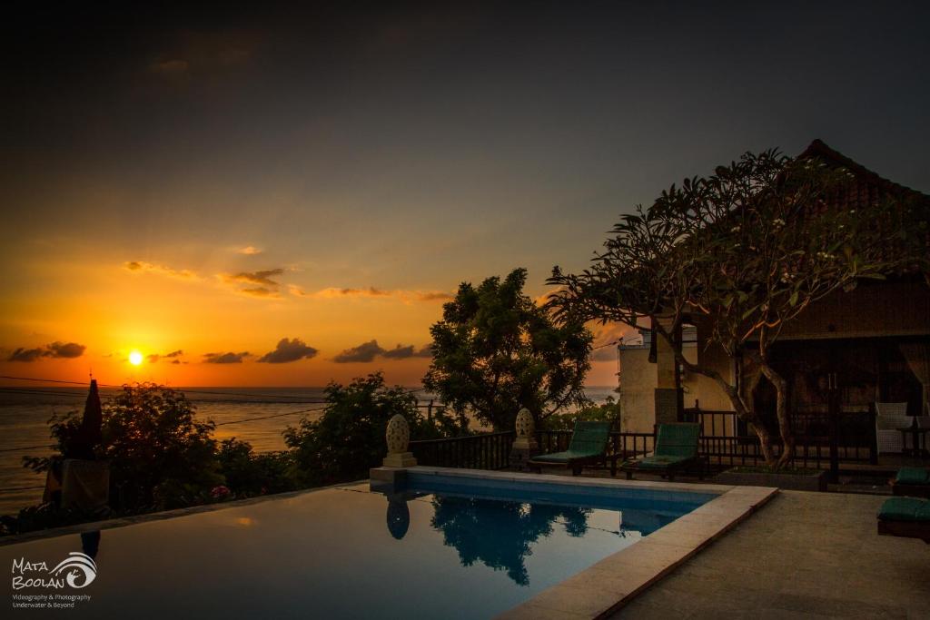 a swimming pool with a sunset in the background at Beten Waru Bungalow and Restaurant in Amed