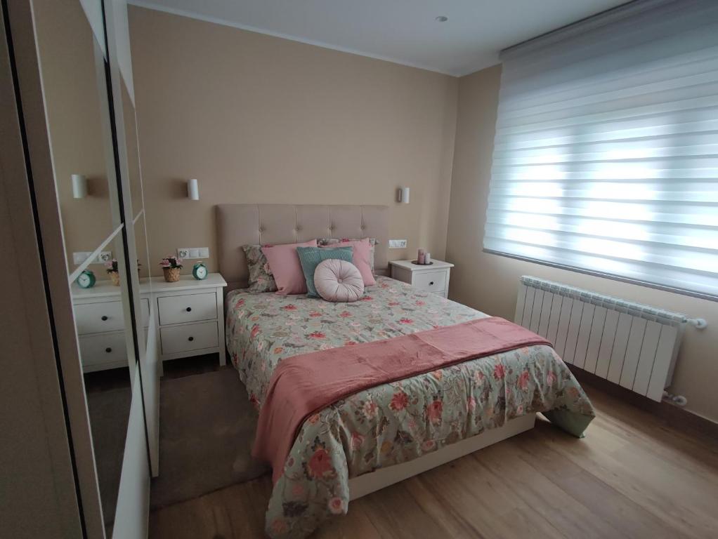 a bedroom with a bed with a pink blanket and a window at APARTAMENTO GAEL- PLAZA ESPAÑA in Avilés