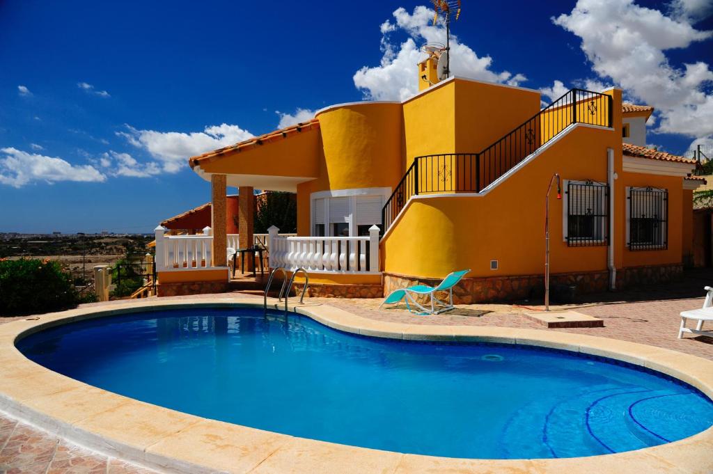 una casa amarilla con piscina frente a ella en Villa Canamon en Mutxamel