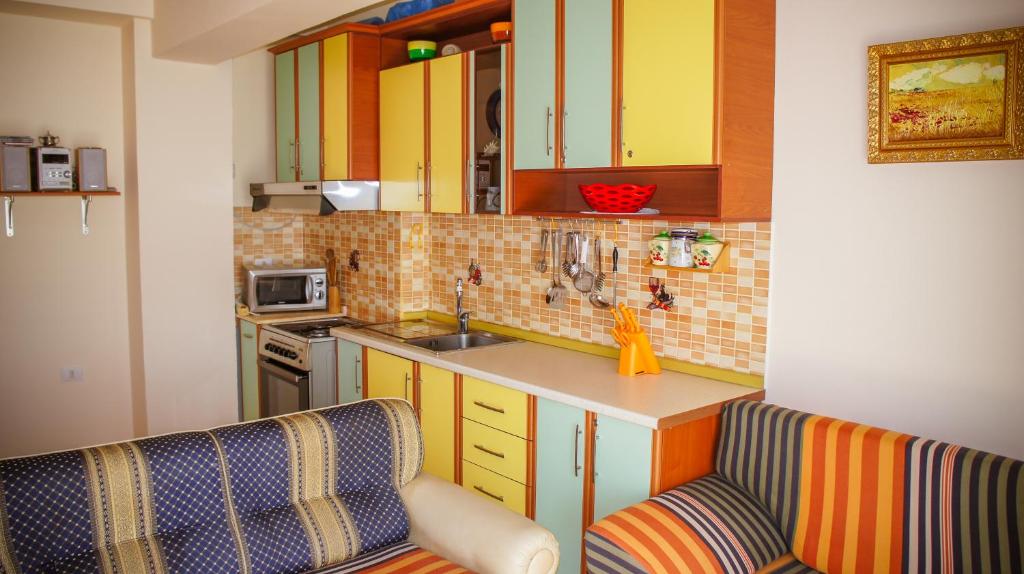 a small kitchen with yellow cabinets and a counter at Nada SeaView Apartment in Shëngjin