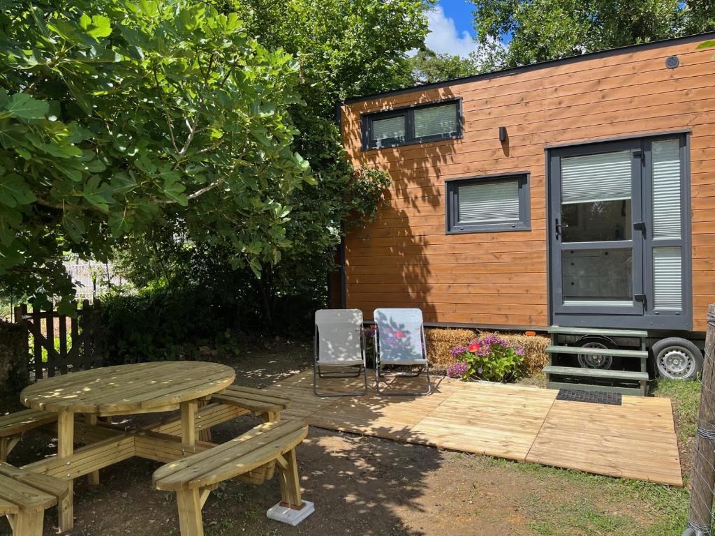 una mesa de picnic y sillas frente a una casa pequeña en La Tiny du paradis en Baigts-de-Béarn