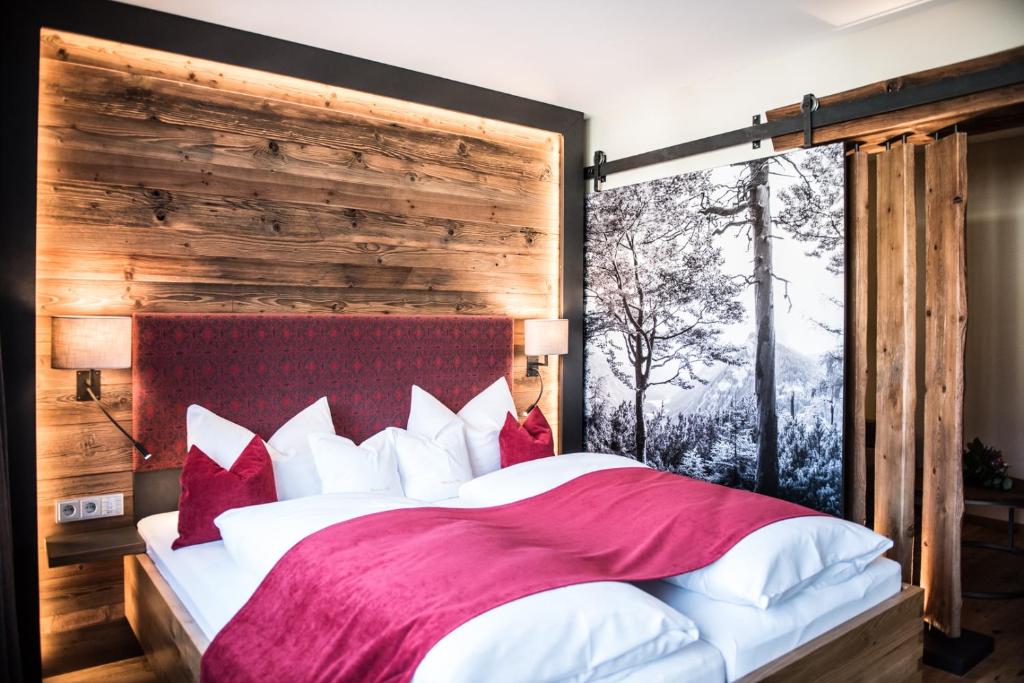 a bedroom with a large bed with red and white pillows at Hotel zur Post in Ruhpolding