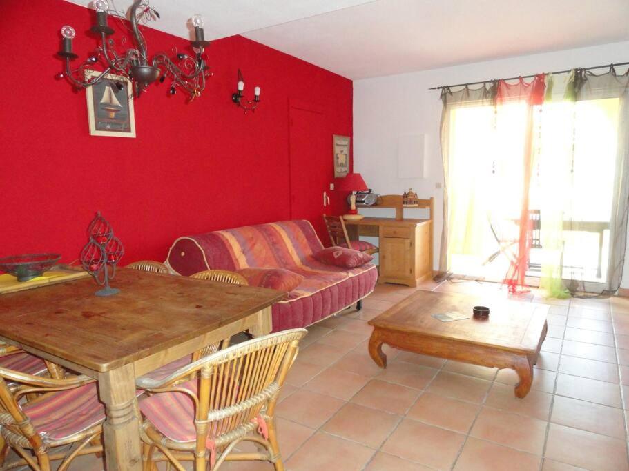 - un salon avec des murs rouges, une table et un canapé dans l'établissement Villa 30, La Palmeraie au village naturiste, au Cap d'Agde