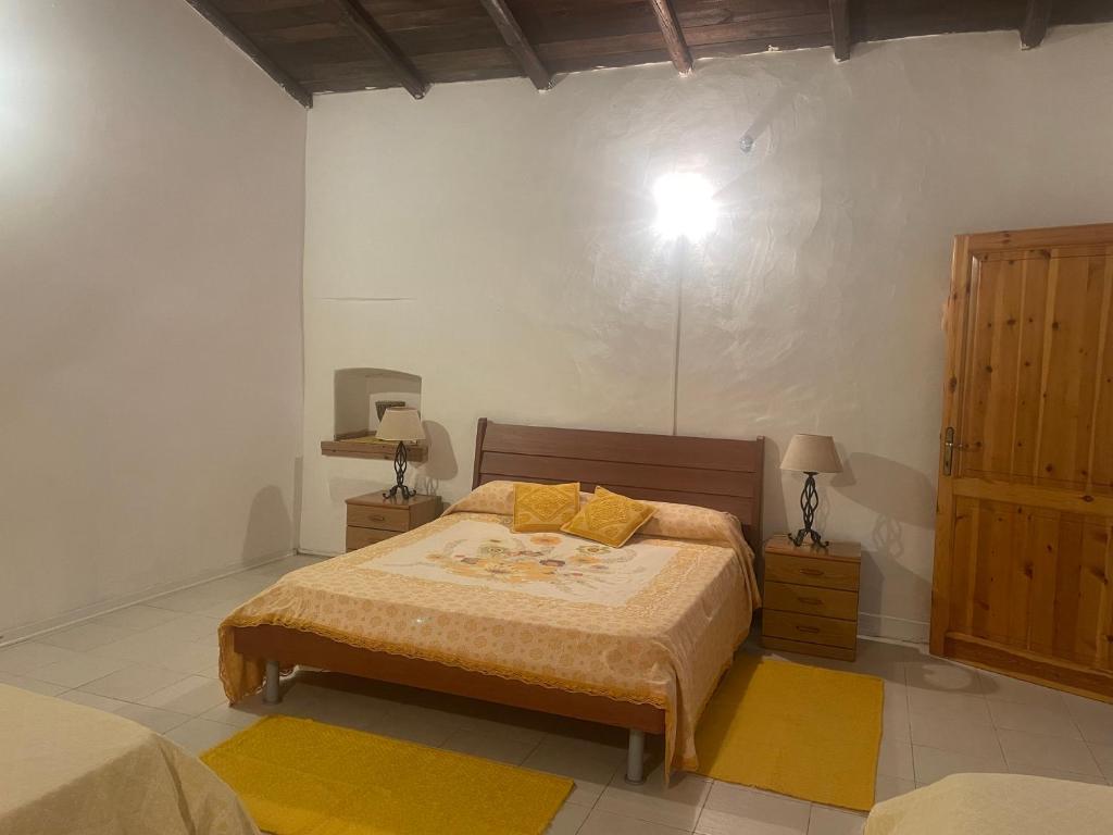 La casa di Simona في Telti: غرفة نوم بسرير واضاءة على الحائط