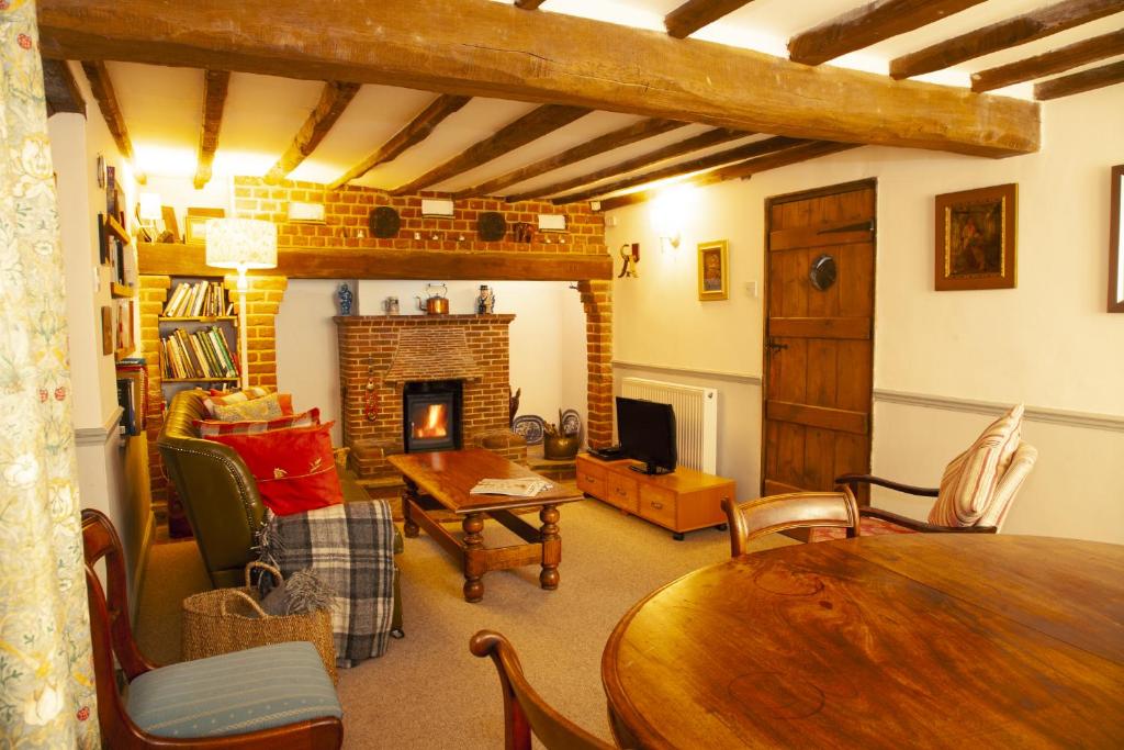 a living room with a table and a fireplace at The Cottage in Cross in Hand