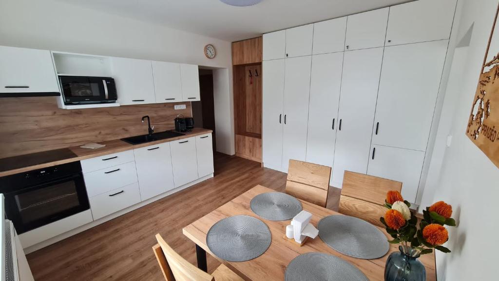 cocina con armarios blancos, mesa y sillas en Horský apartmán Karlovice en Karlovice