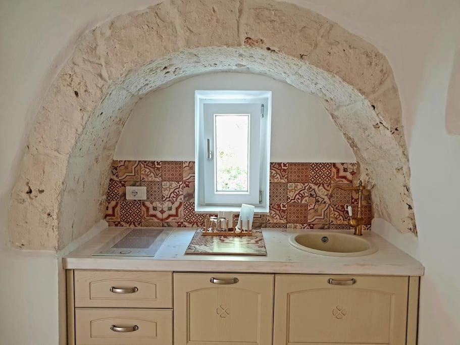 baño con lavabo y arco de piedra en Trullollero UnPostoNelMondo, en Ceglie Messapica