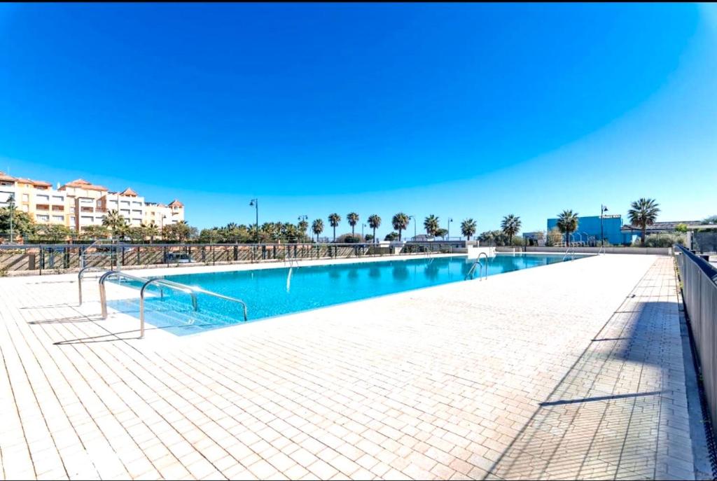 a large swimming pool with palm trees in the background at Los Flamencos Isla Canela CALEFACCIÓN Y WIFI -SOLO FAMILIAS Y PAREJAS- in Isla Canela