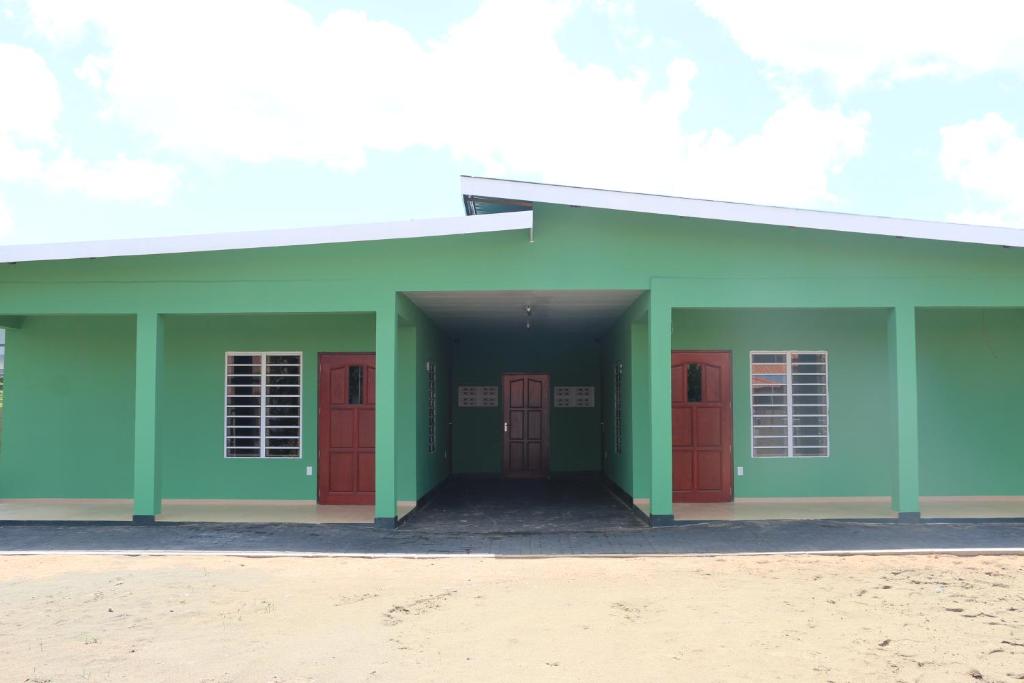 un edificio verde e rosso con porte rosse di Schitterend gelegen tweekamerwoning a Paramaribo
