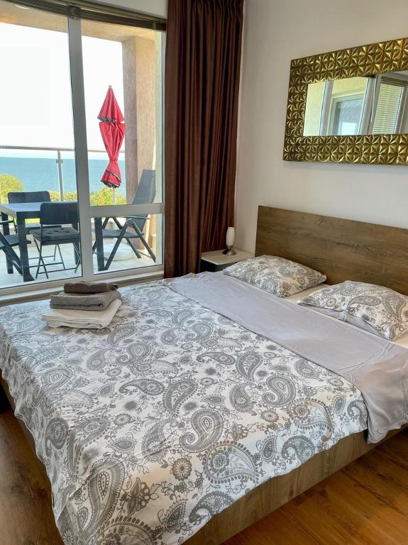 a bedroom with a bed with a view of the ocean at Byla Sun Day Apartament in Byala