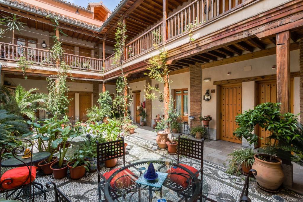 un patio esterno con tavoli, sedie e piante in vaso di Abadía Hotel a Granada
