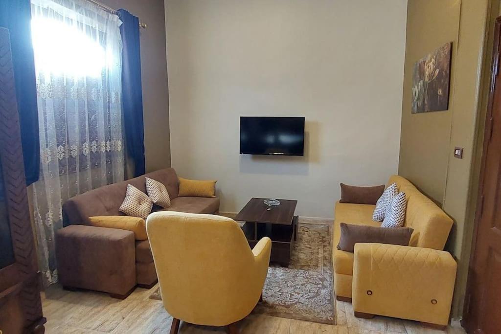 a living room with a couch and chairs and a tv at Sweet home 1 in Mansoura