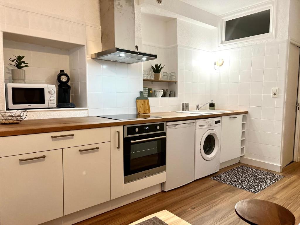 a kitchen with white cabinets and a washer and dryer at Collioure, centre ville, joli T2 in Collioure