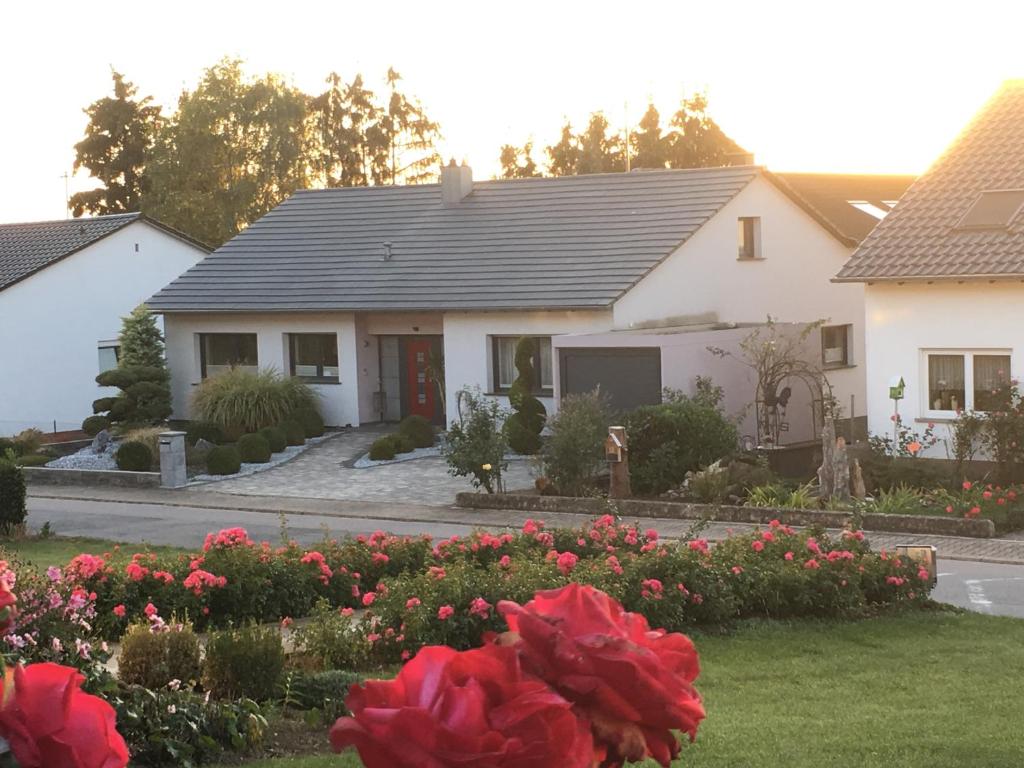 een wit huis met rode bloemen in een tuin bij DreiländerOase in Perl