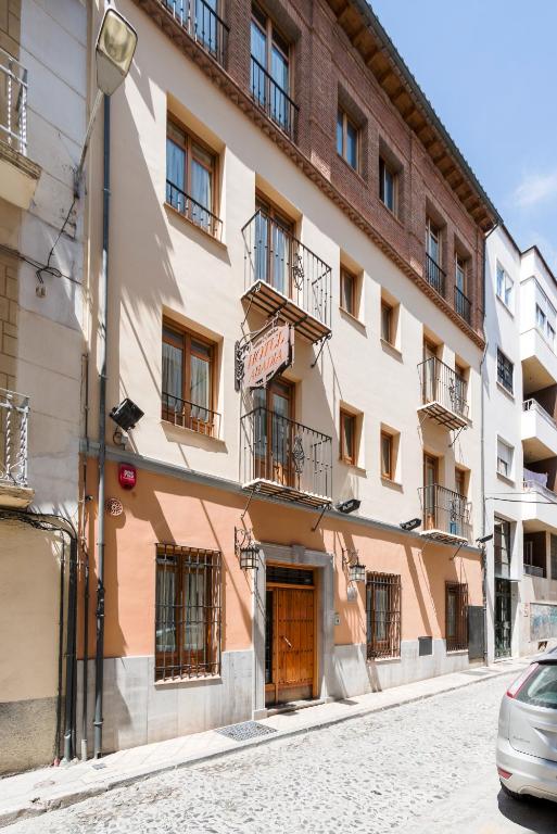 un edificio en una calle con un coche aparcado delante en Abadía Hotel, en Granada