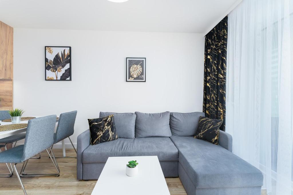un soggiorno con un divano blu e un tavolo di Apartament D-07 "NAWIGATOR" Kołobrzeg by Holiday&Sun a Kołobrzeg