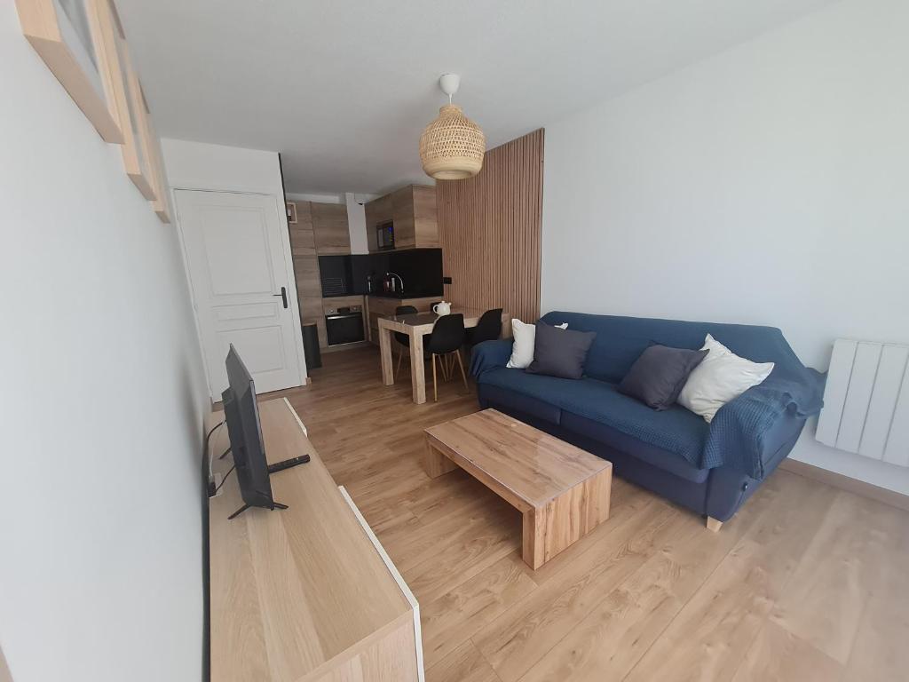 a living room with a blue couch and a table at Charmant 2 pièces centre station in Valberg