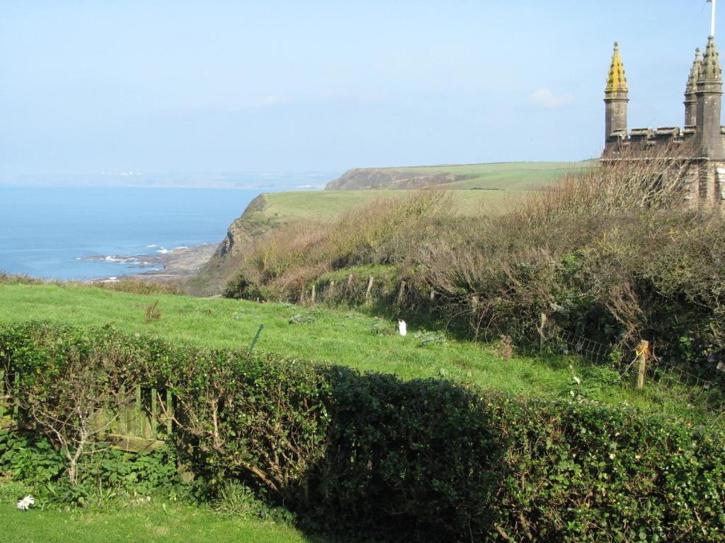 a grassy hill with a castle and the ocean at Church Cottage in Bude