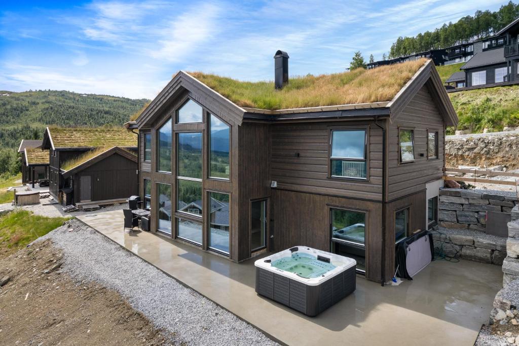 ein Haus mit einem Grasdach und einem Whirlpool in der Unterkunft The Panorama Retreat - Rindabotn Cabin in Sogndal