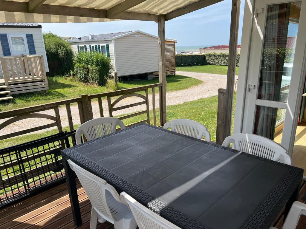 - une table et des chaises noires sur une terrasse couverte dans l'établissement GRAIN DE SABLE - Mobil Home climatisé 5 pers - 100m de la mer - Le Portel, à Le Portel