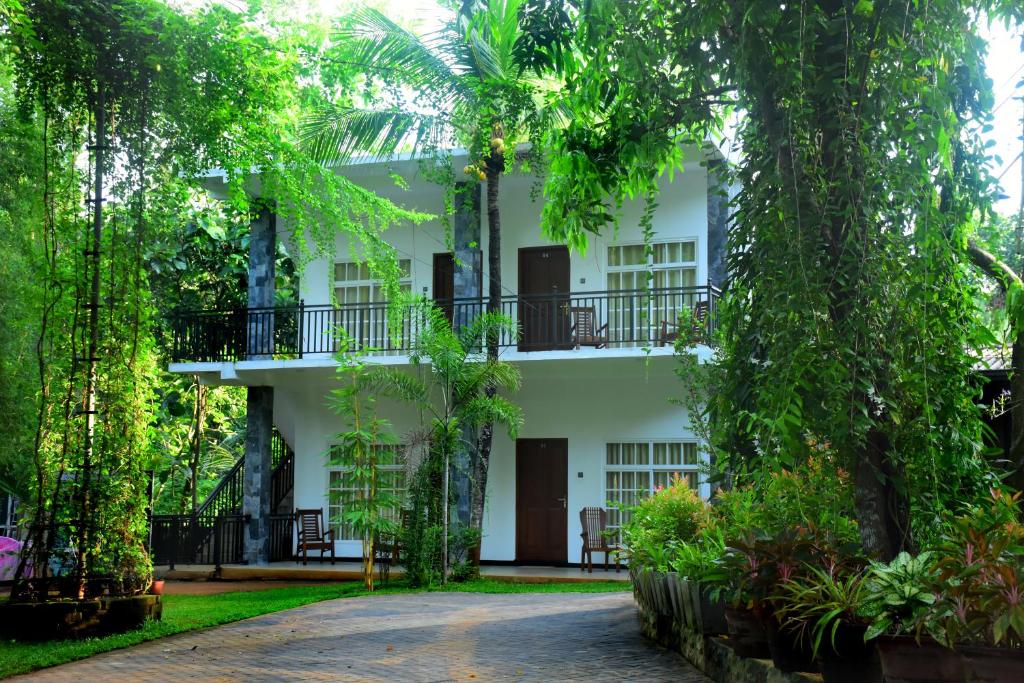 un edificio blanco con árboles delante de él en Imperial Resort en Udawalawe