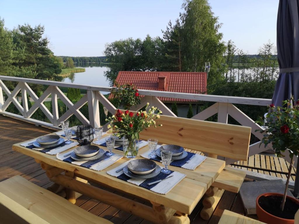 une table en bois avec des assiettes et de la vaisselle sur une terrasse dans l'établissement Mazuria Inulec, à Mikołajki