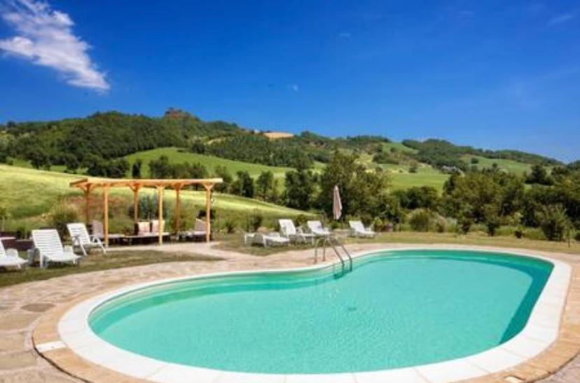 a large swimming pool with chairs and a gazebo at Agriturismo Dai Du Bourdei in Frontino